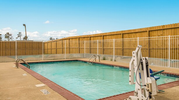 Une piscine entourée d’une clôture en bois, un poste de surveillance pour les sauveteurs et un ciel dégagé.