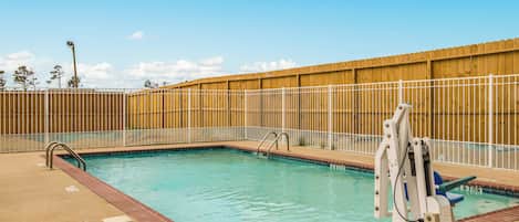 A swimming pool with a wooden fence, a lifeguard stand, and a clear sky.