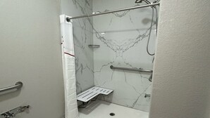 A modern bathroom with a shower, grab bars, and a white shower curtain.