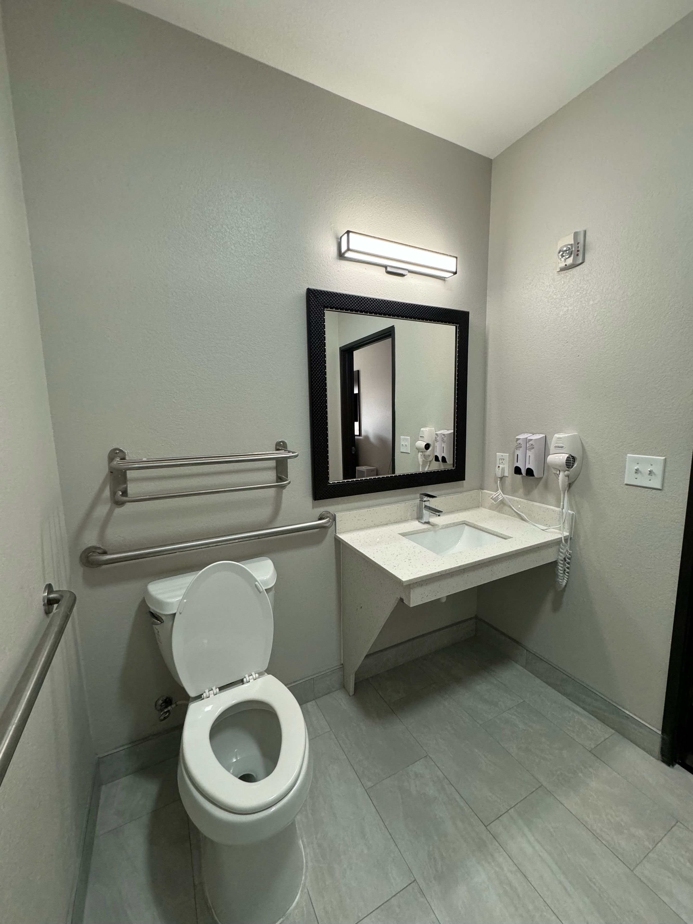 Un baño moderno con inodoro, lavamanos y espejo.