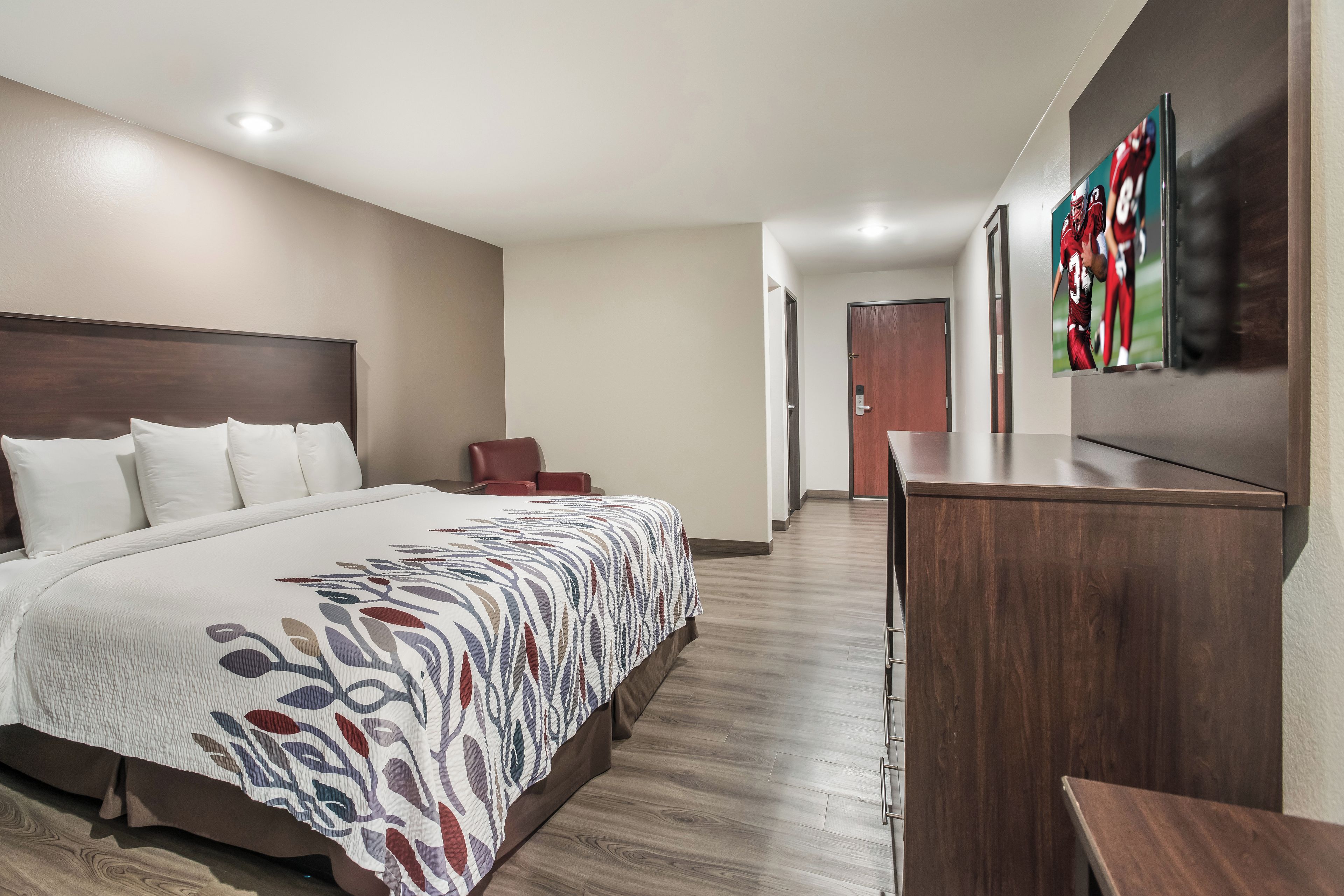 Habitación de hotel con una cama grande, un escritorio y una silla. Hay una puerta que conduce a otra habitación.