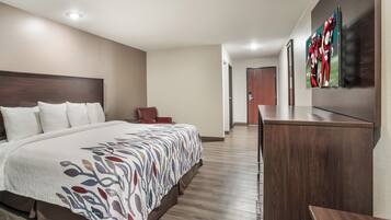 Habitación de hotel con una cama grande, un escritorio y una silla. Hay una puerta que conduce a otra habitación.