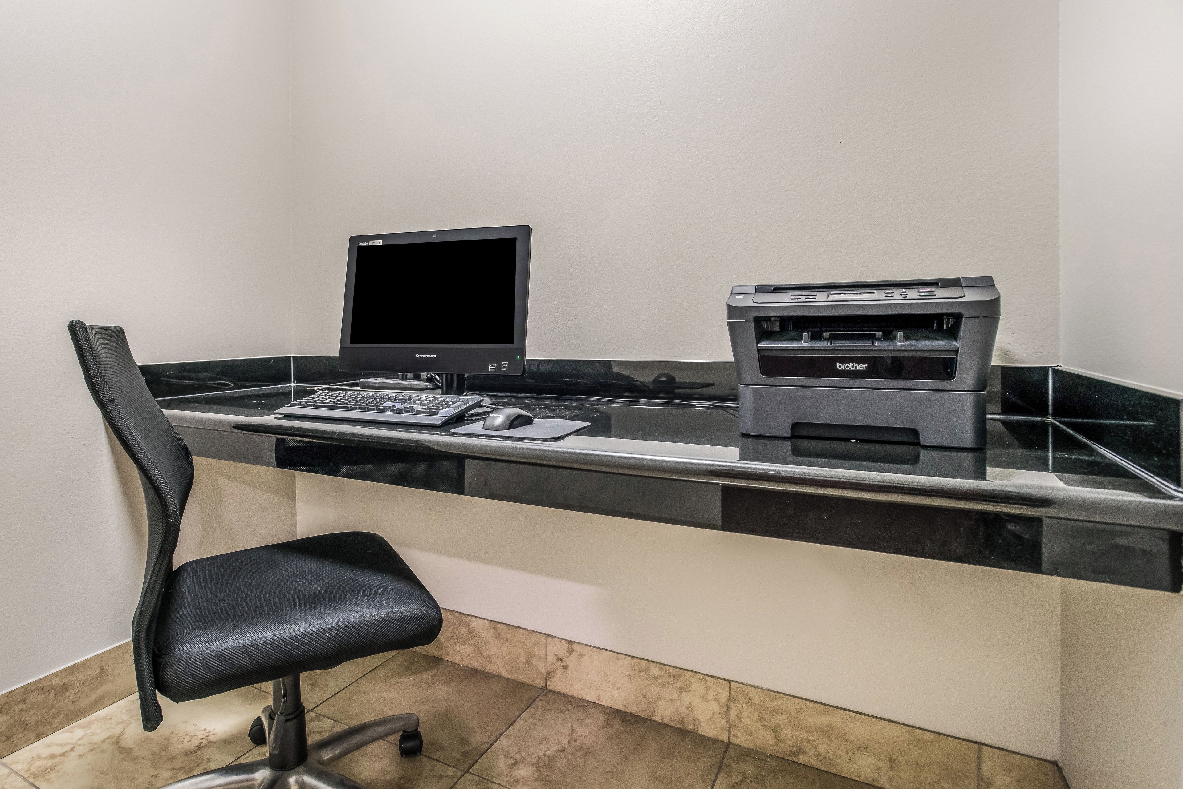 A workspace with a desktop computer, a printer, and a chair.