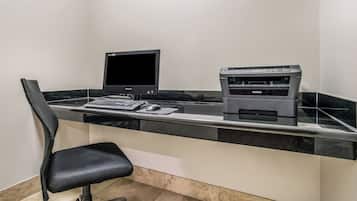 Un espacio de trabajo con un ordenador de escritorio, una impresora y una silla.