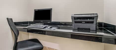 A workspace with a desktop computer, a printer, and a chair.