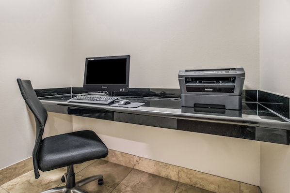 Un espacio de trabajo con un ordenador de escritorio, una impresora y una silla.