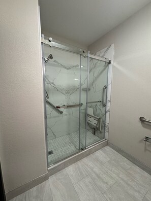 A modern bathroom with a glass-enclosed shower, marble walls, and a tiled floor. - Red Roof Inn & Suites Lake Charles (Lake Charles)