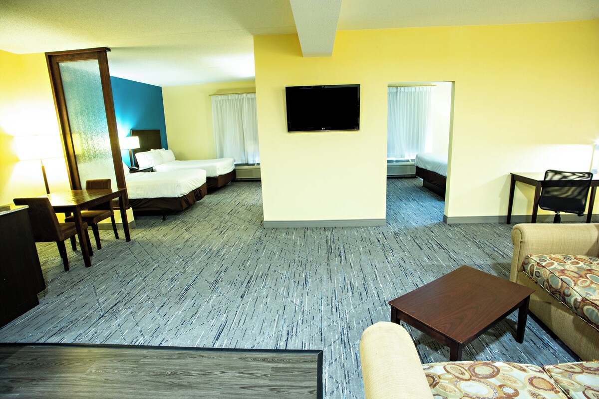 Una habitación de hotel con cama, escritorio, silla, sofá y televisor.