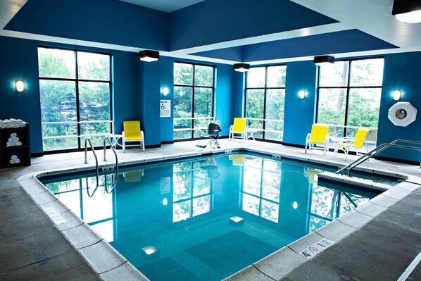 Una piscina con agua azul cristalina, rodeada de muros azules y grandes ventanales.