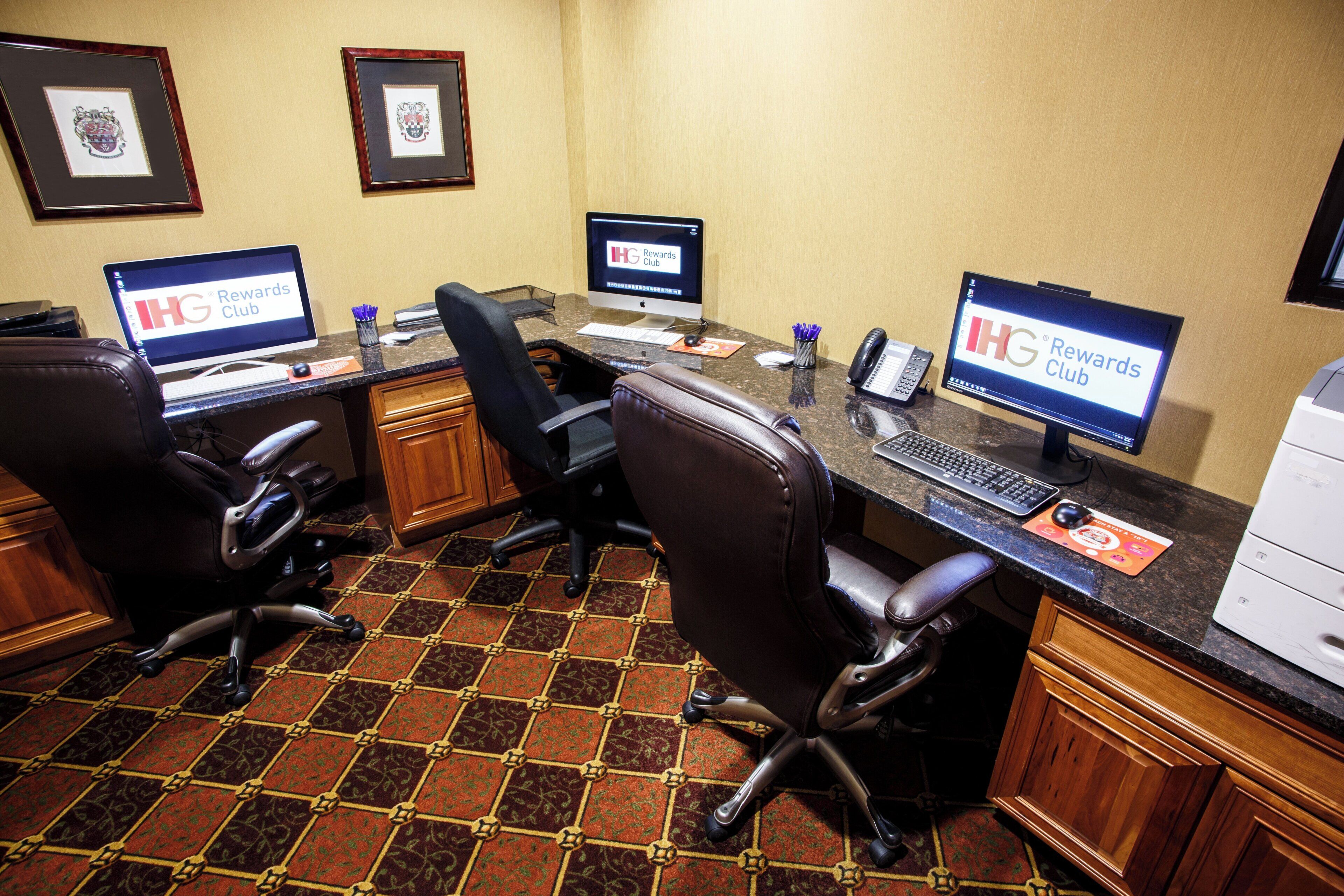A conference room with three desks, each with a computer and a chair.
