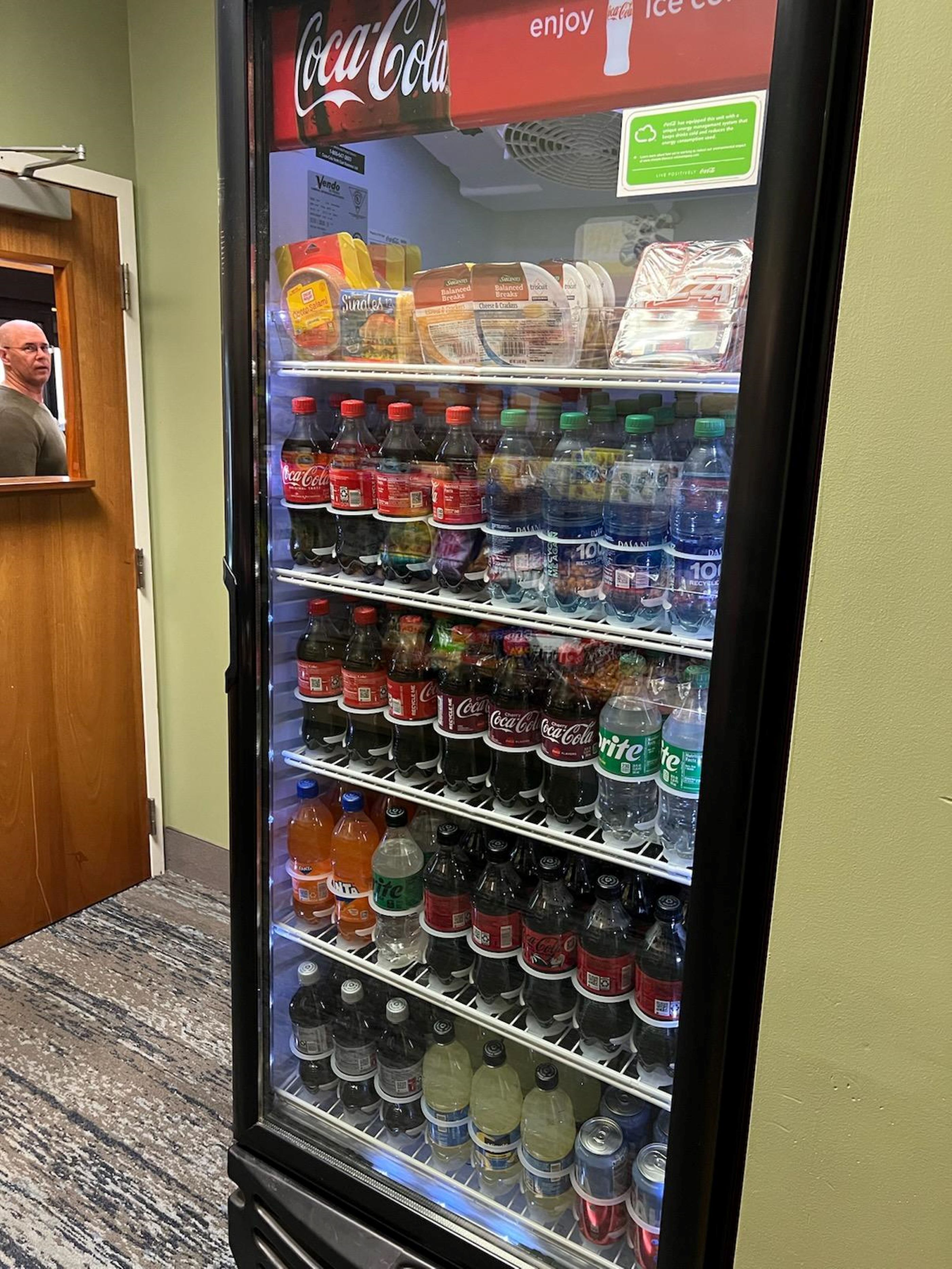 Máquina expendedora con diversas bebidas, incluyendo Coca-Cola, Sprite y otras gaseosas.