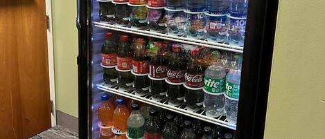 A vending machine stocked with various beverages including Coca-Cola, Sprite, and other sodas.