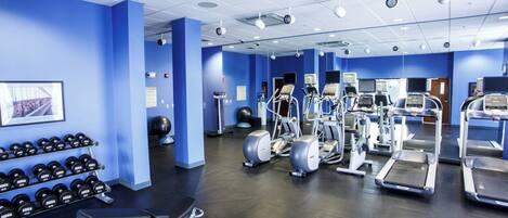 A gym with exercise equipment, dumbbells, and a treadmill.