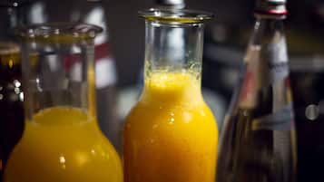 Three glass bottles with a yellow liquid, likely juice, in a bar setting.