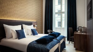 Ett hotellrum med en stor säng, ett skrivbord och utsikt över staden genom fönstret.