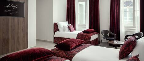 Habitación de hotel con dos camas, ropa de cama roja y blanca, un revestimiento de pared de madera, un televisor y vistas a la calle.