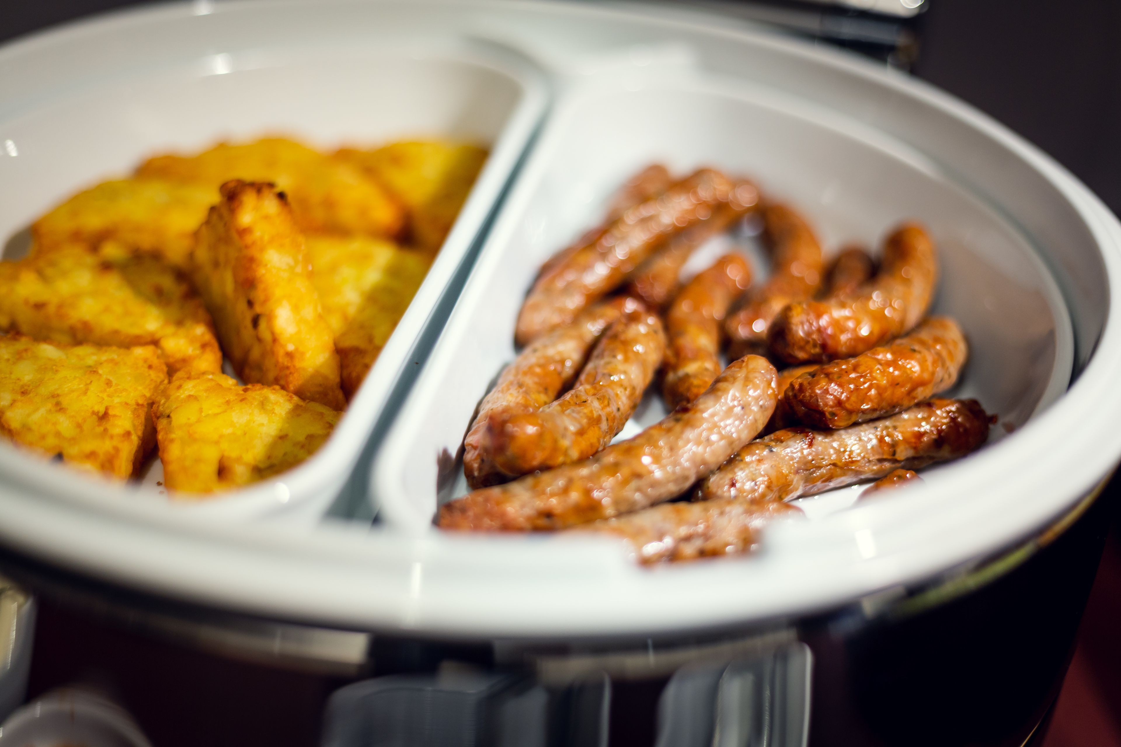 En buffet med to afdelinger: en med gyldenbrune ristede kartofler og en anden med grillpølser.