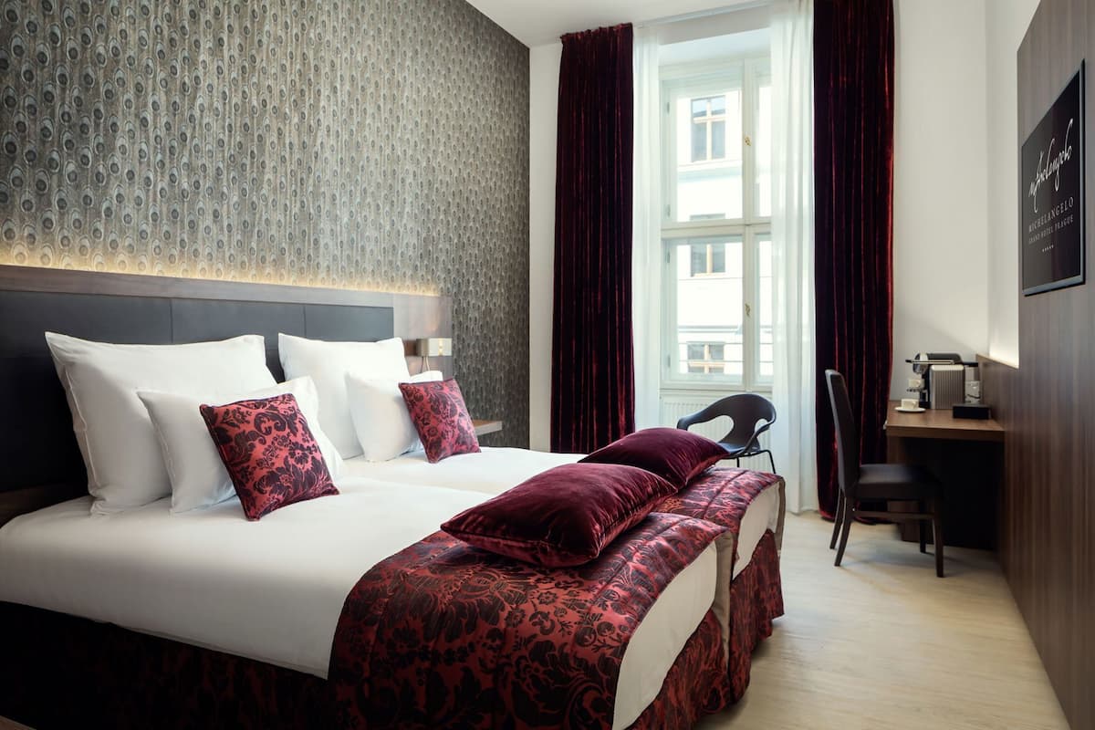 Habitación de hotel con una cama grande, un escritorio y vistas a la ciudad.