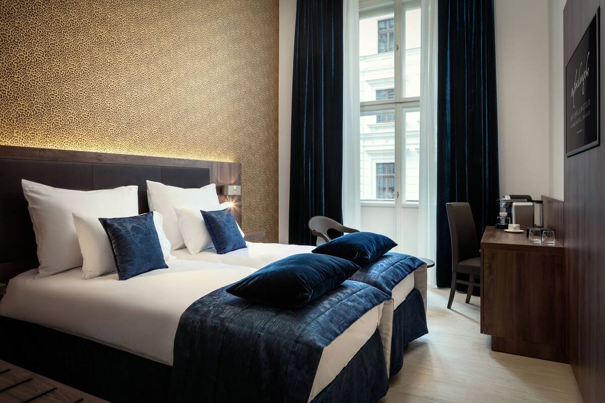 Una habitación de hotel con una cama grande, un escritorio y vistas a edificios a través de la ventana.