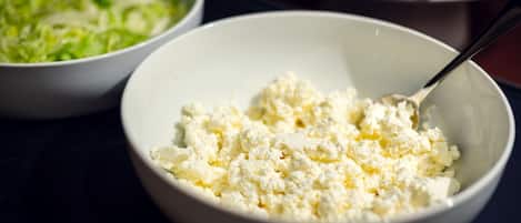 Two bowls on a table, one with shredded lettuce and the other with crumbled cheese.