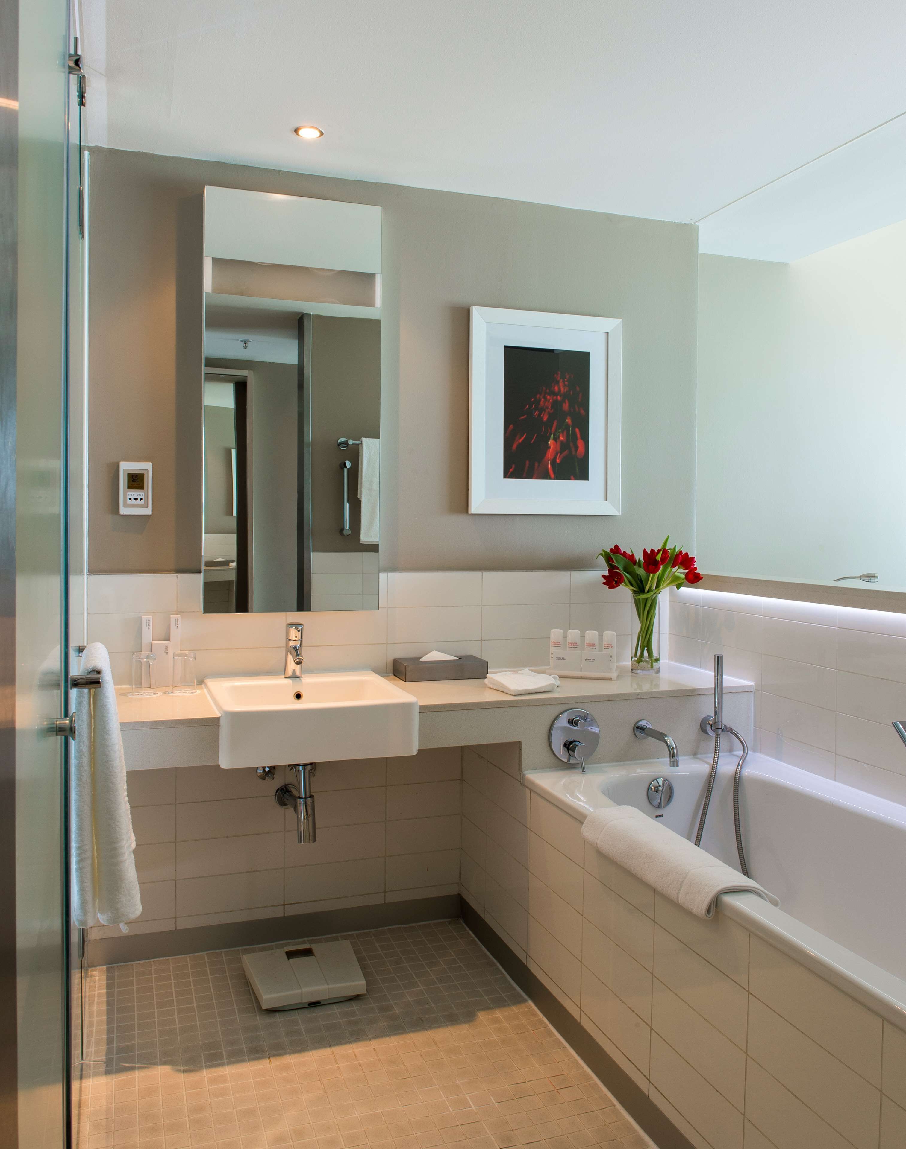 A modern bathroom with a glass shower enclosure, a sink, a bathtub, and a mirror.