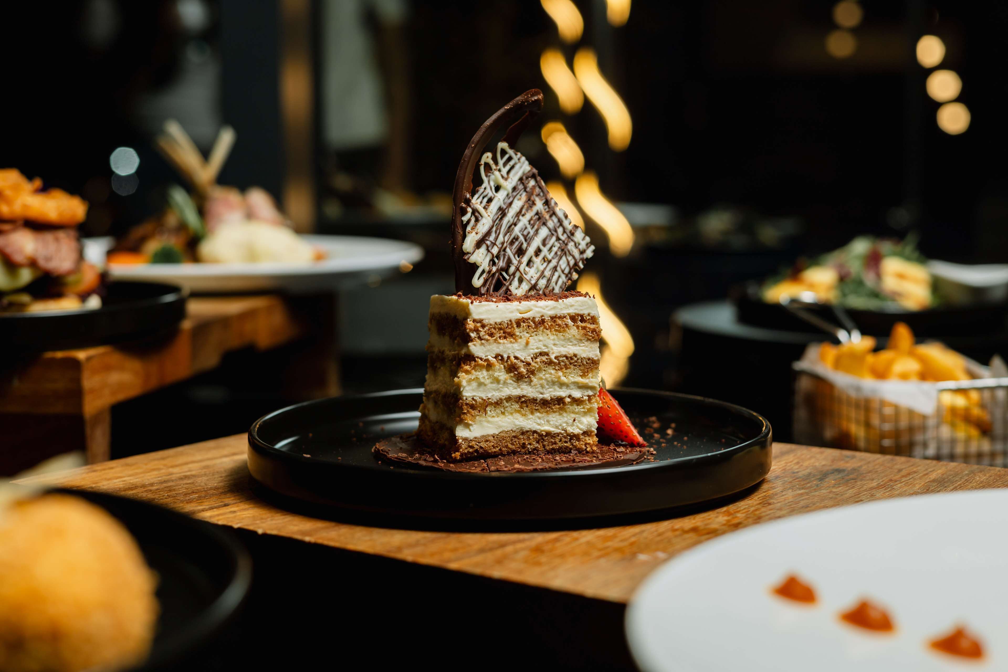 A dessert with multiple layers and a chocolate decoration on a plate.