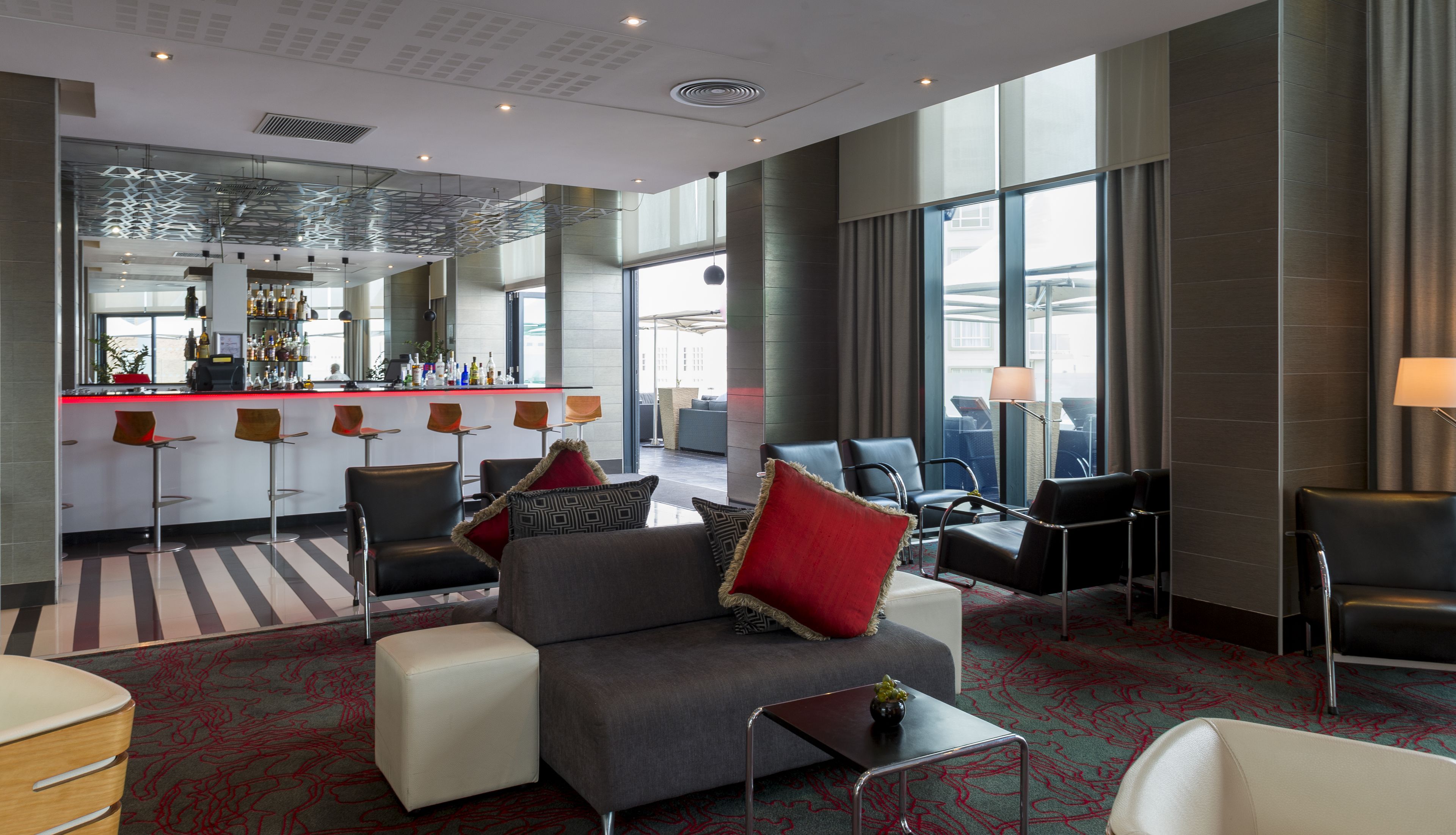 A modern hotel lobby with a bar area, seating, and large windows.
