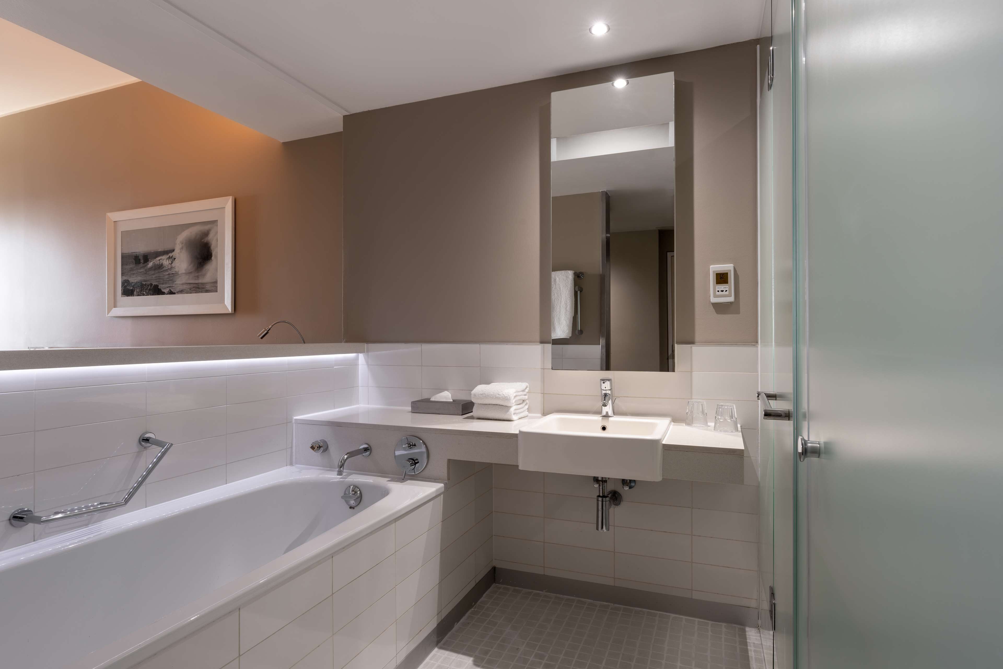 Un baño moderno con una bañera grande, un lavabo y un espejo.