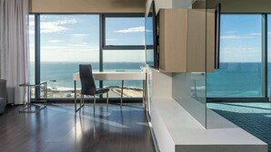Une chambre d’hôtel moderne dotée d’une grande fenêtre donnant sur l’océan et la plage.