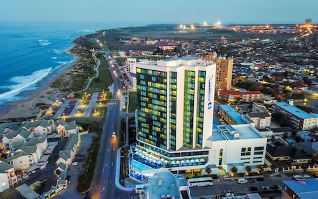A hotel with a modern design, located near a beach with a view of the ocean.