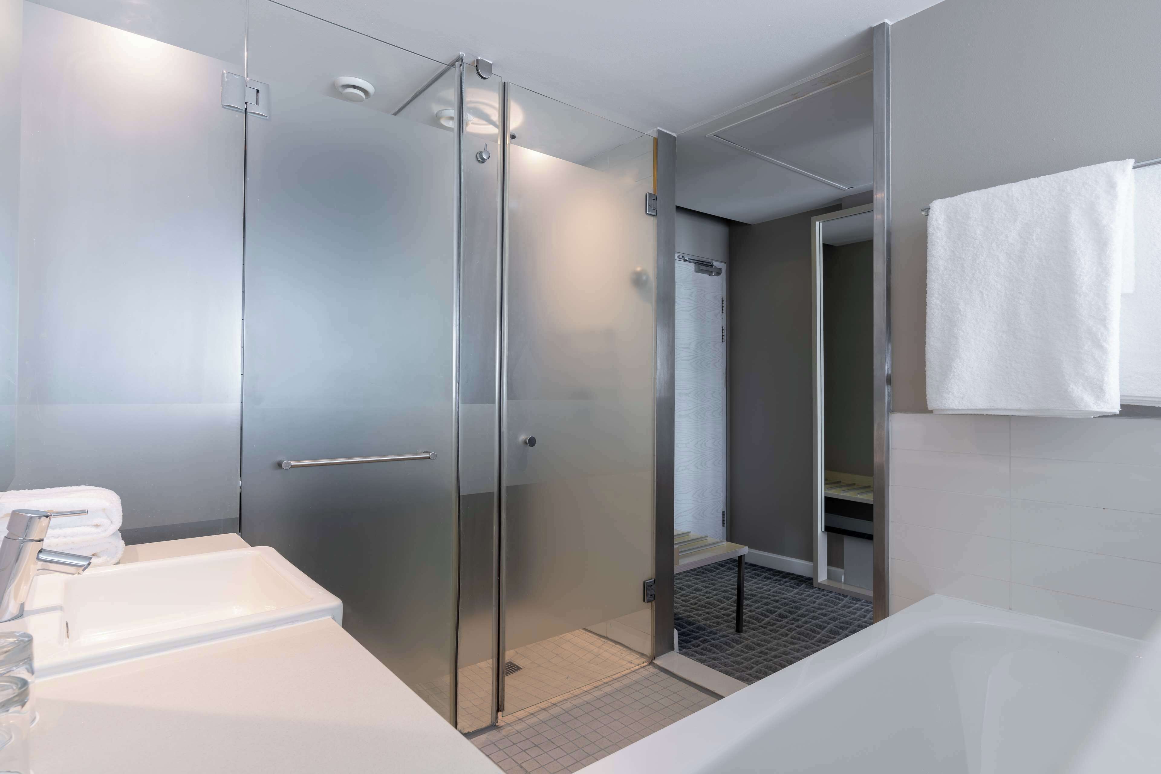 Ein modernes Badezimmer mit einer Duschkabine aus Glas, einem weißen Waschbecken und einer Badewanne.