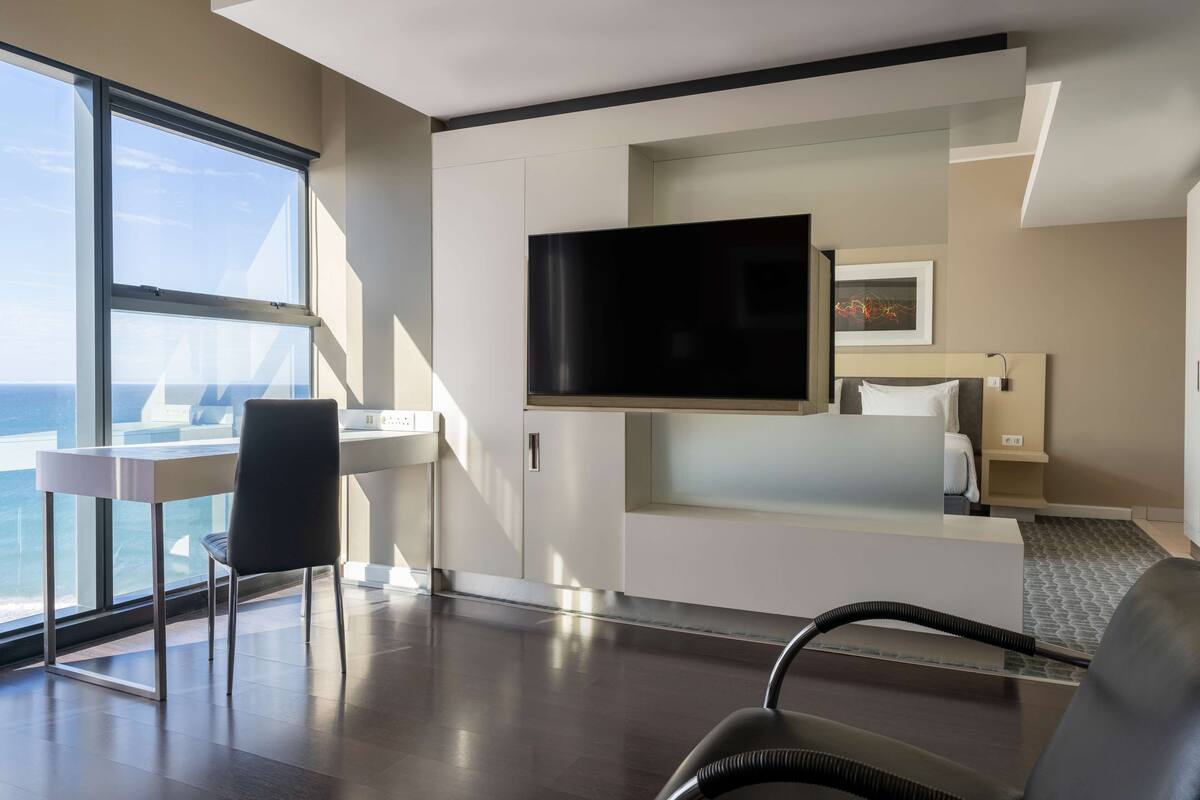 Ein modernes Hotelzimmer mit einem großen Fernseher, einem Schreibtisch und einem Stuhl.