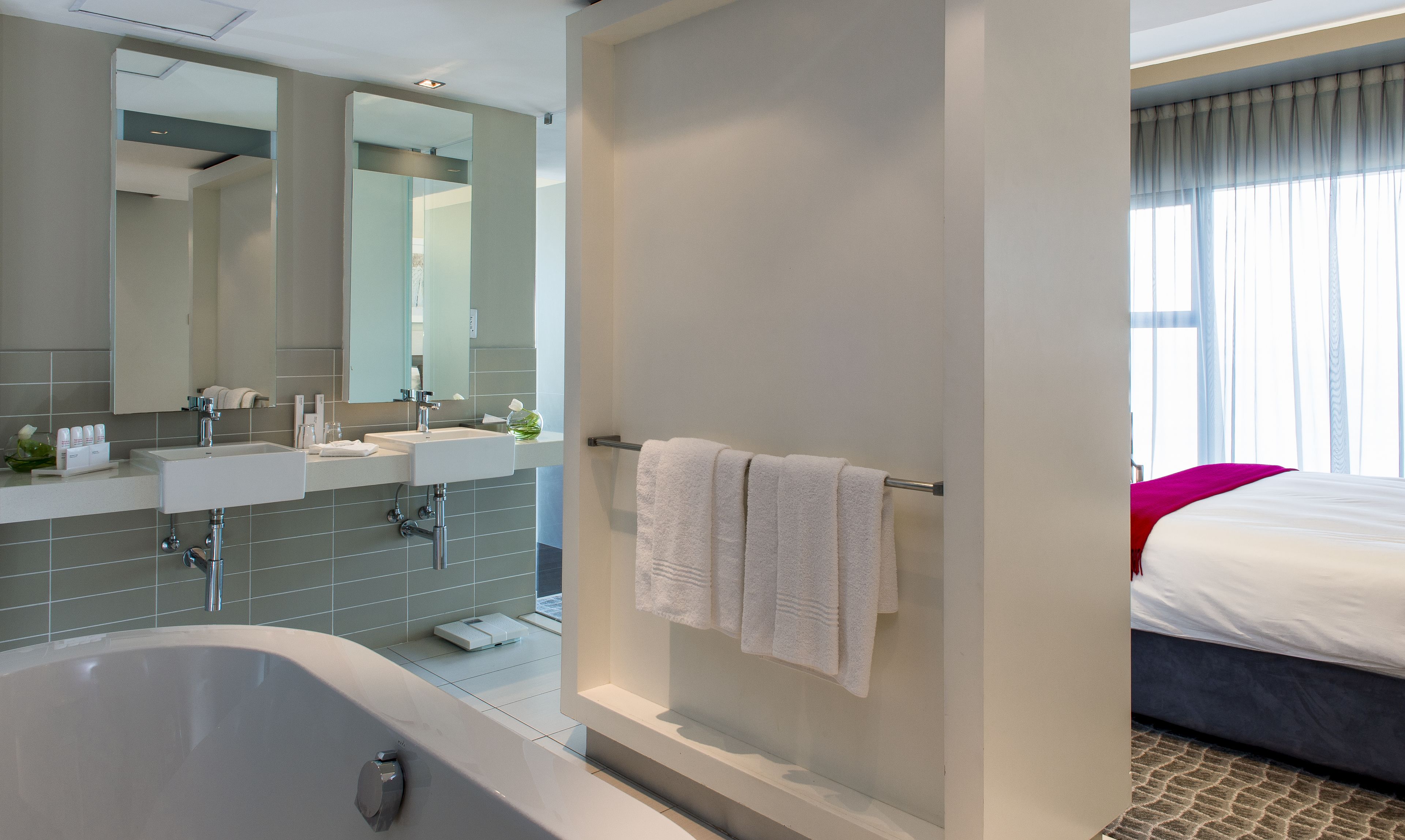 A modern bathroom with a bathtub, two sinks, and a large mirror.