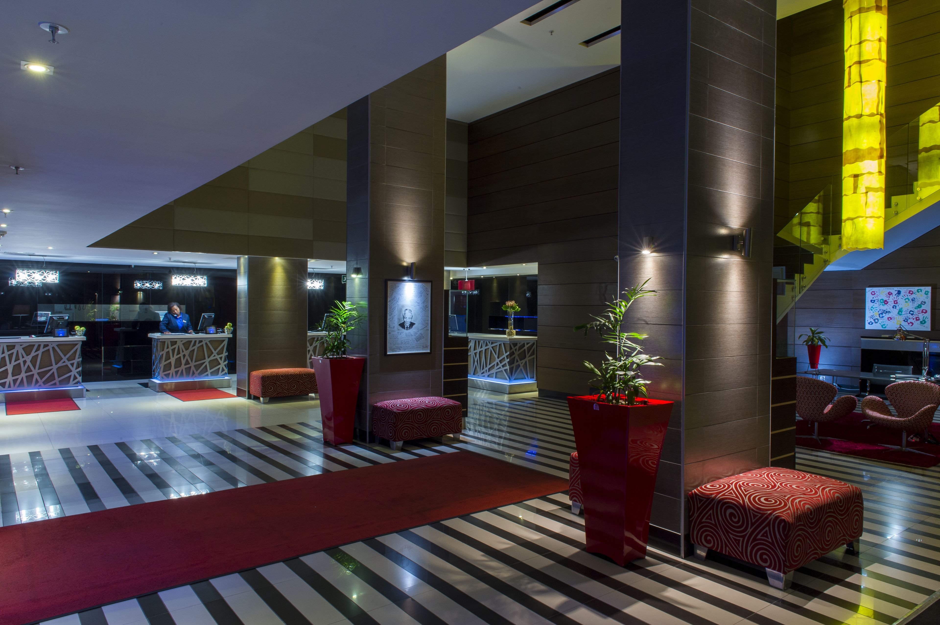 A modern lobby with a red carpet, seating areas, and a staircase with illuminated steps.