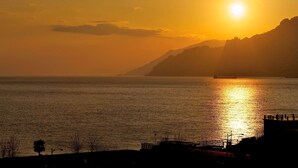A sunset over a calm sea with a silhouette of a mountain range in the background. - Hotel Novotel Salerno Est Arechi (Salerno)