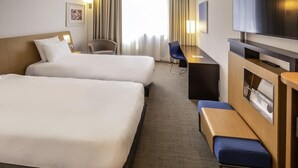 A hotel room with two beds, a desk, a chair, a TV, and a window with curtains. - Hotel Novotel Salerno Est Arechi (Salerno)