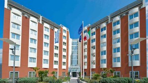 Un hotel moderno con entrada principal, varios pisos y banderas.