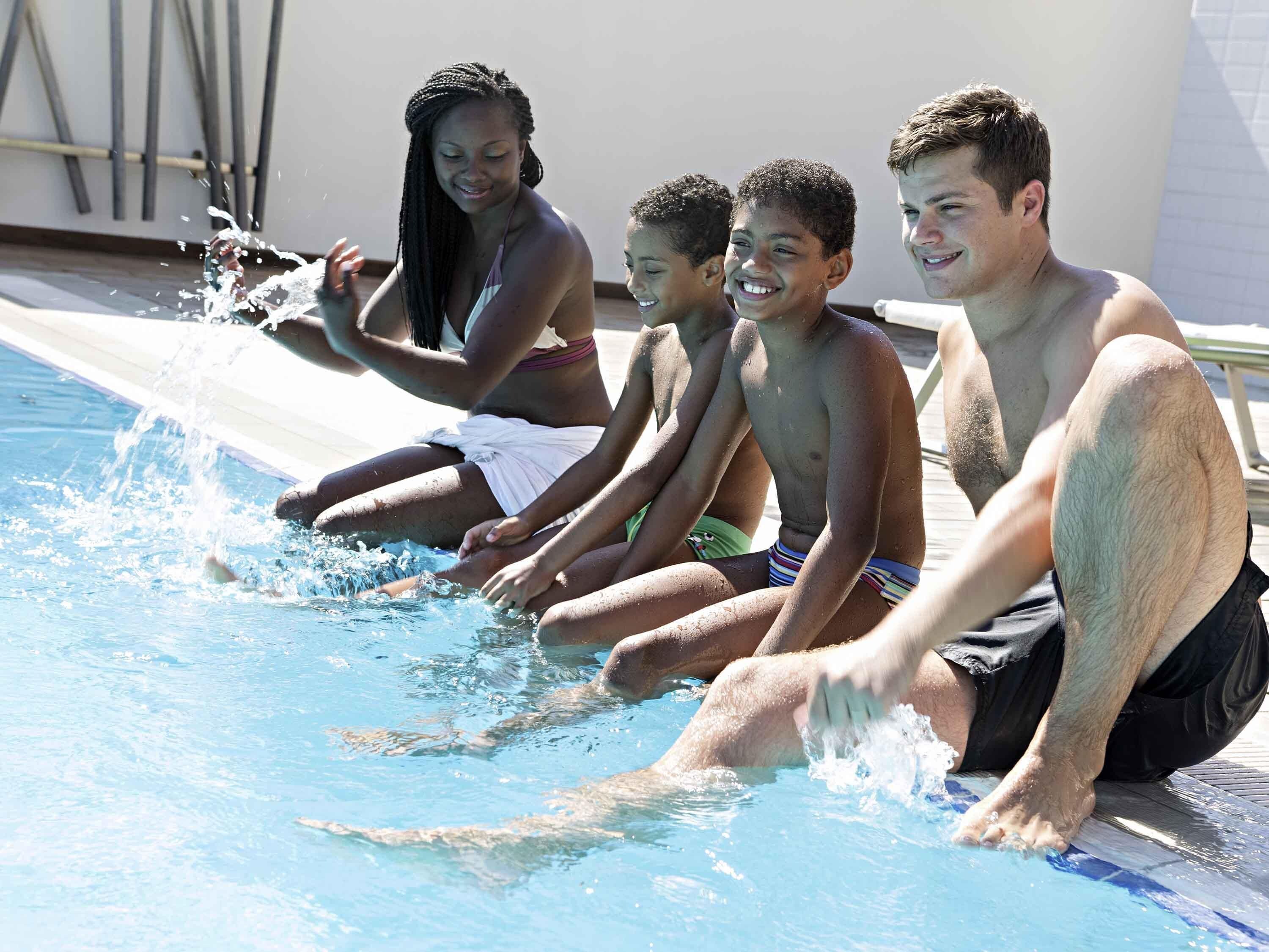 Un grupo de personas sentadas junto a una piscina, con salpicaduras de agua a su alrededor.