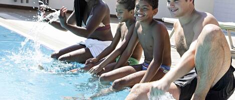 A group of people sitting by a pool with water splashing around them.