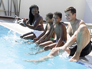 Un grupo de personas sentadas junto a una piscina, con salpicaduras de agua a su alrededor.