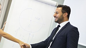 Two people shaking hands in front of a whiteboard with diagrams. - Hotel Novotel Salerno Est Arechi (Salerno)