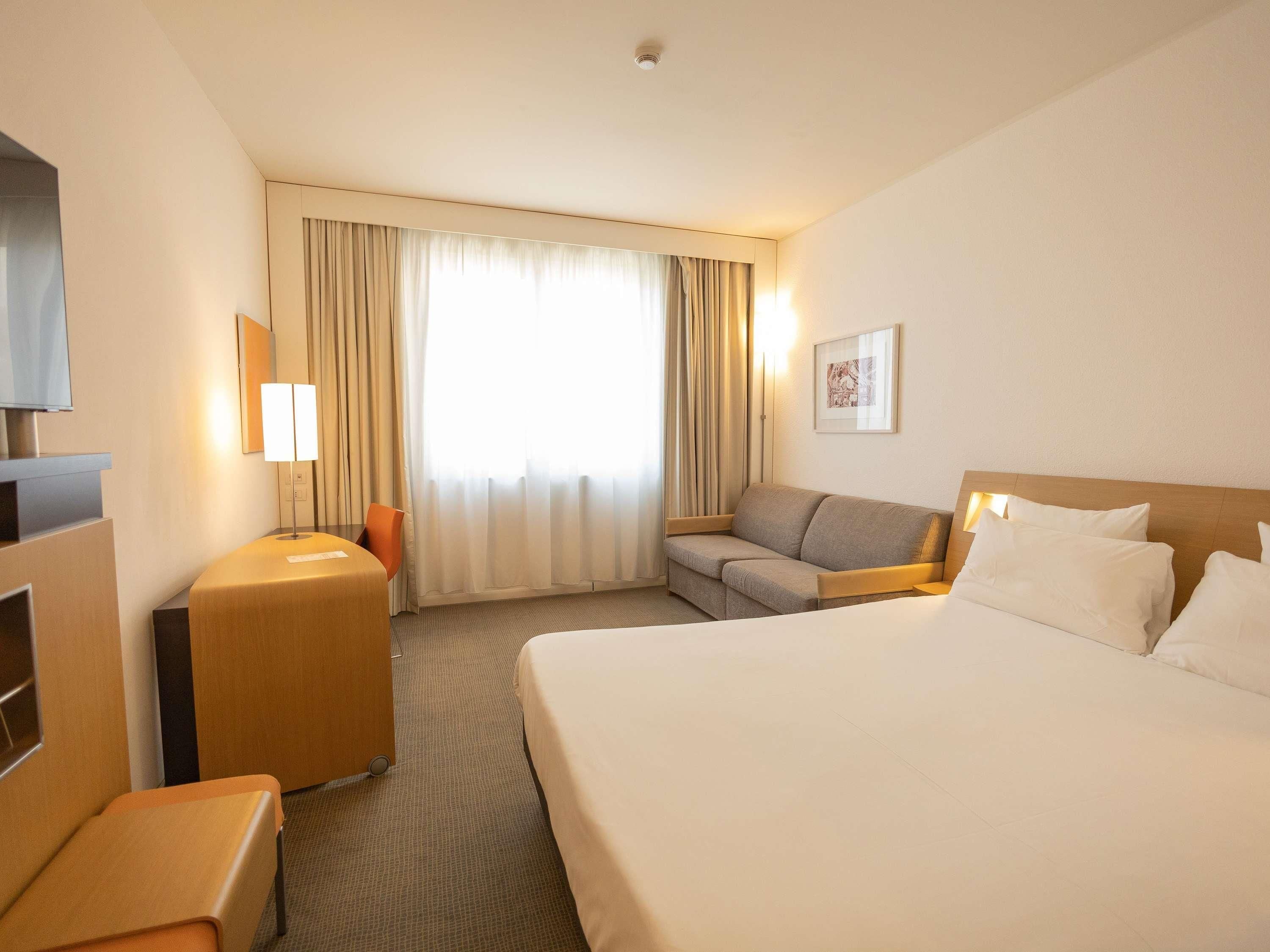 Ein Hotelzimmer mit Bett, Sofa, Schreibtisch und Fernseher.