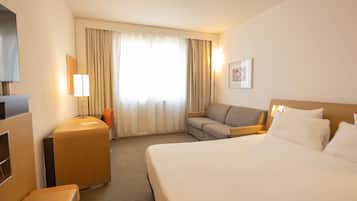 Una habitación de hotel con cama, sofá, escritorio y televisión.