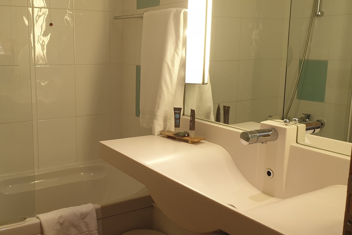 Un baño moderno con bañera, lavabo y espejo.