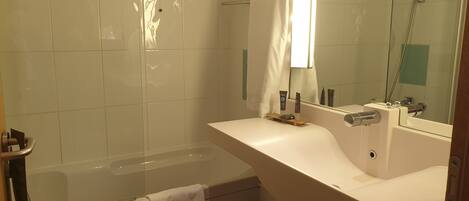 Une salle de bain moderne avec une baignoire, un lavabo et un miroir.