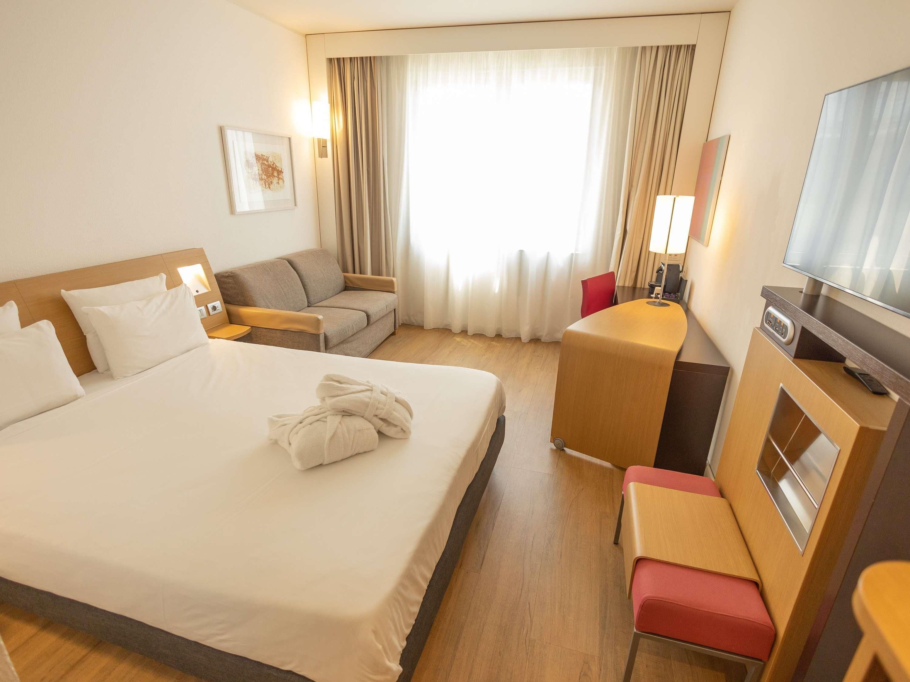 Une chambre d’hôtel avec un grand lit, un canapé, un bureau et une télévision.