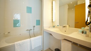 A modern bathroom with a bathtub, a shower, and a vanity with a mirror. - Hotel Novotel Salerno Est Arechi (Salerno)