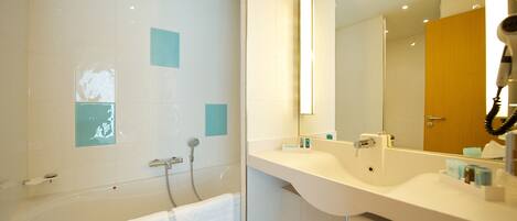 A modern bathroom with a bathtub, a shower, and a vanity with a mirror.