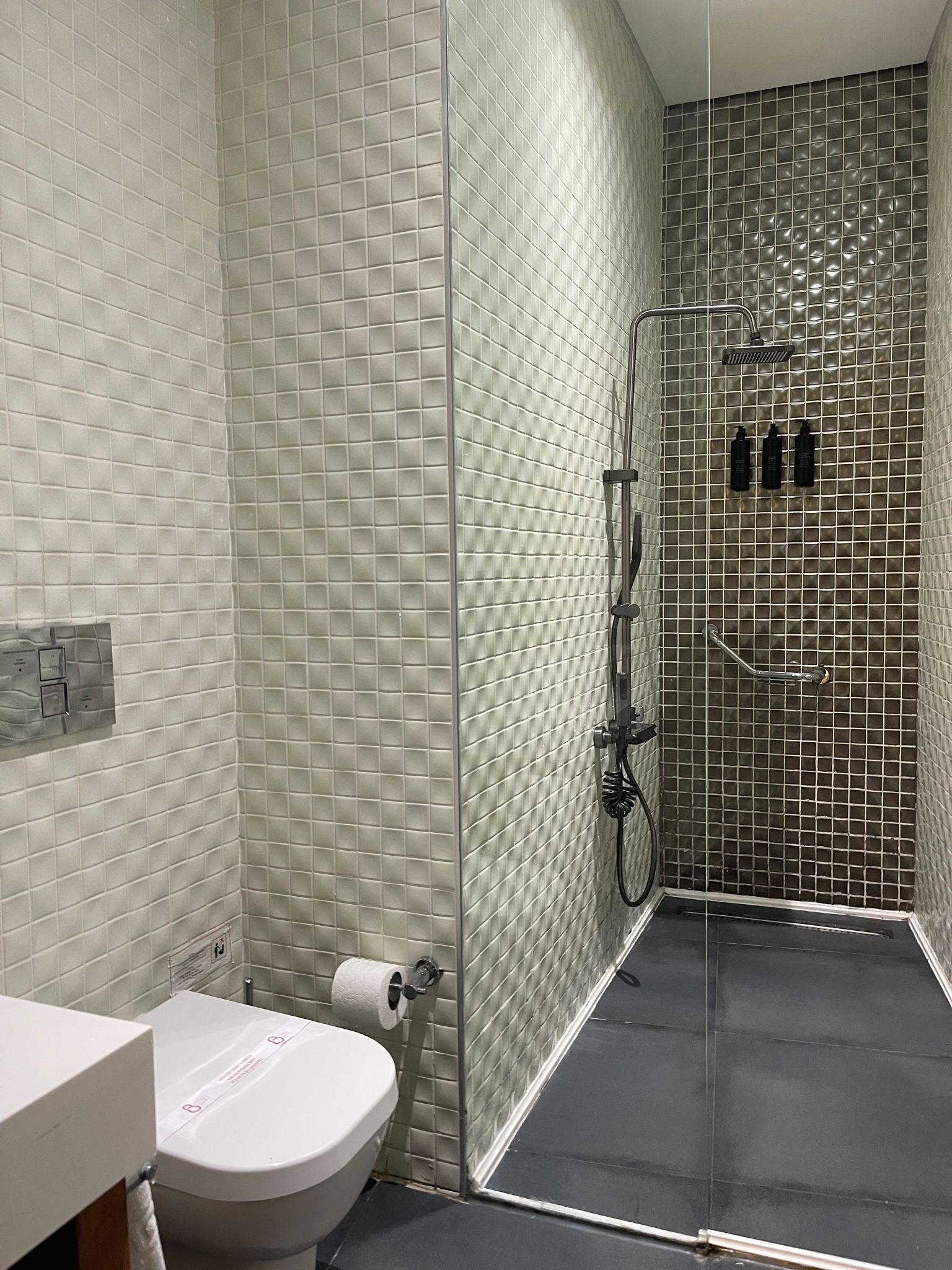 Un baño con inodoro, lavamanos y zona de ducha con puerta de cristal.