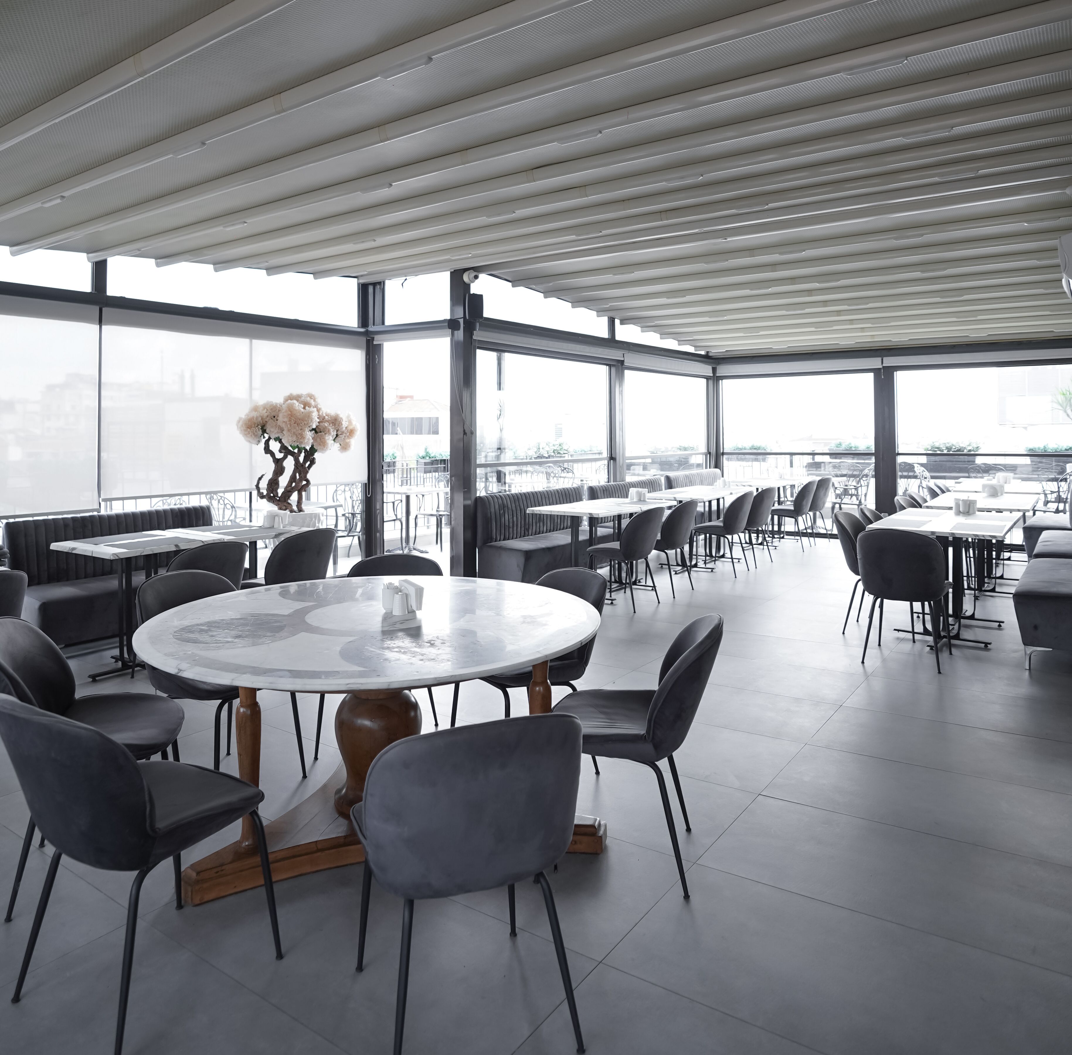 A spacious indoor dining area with high ceilings, large windows, and a view of the cityscape.